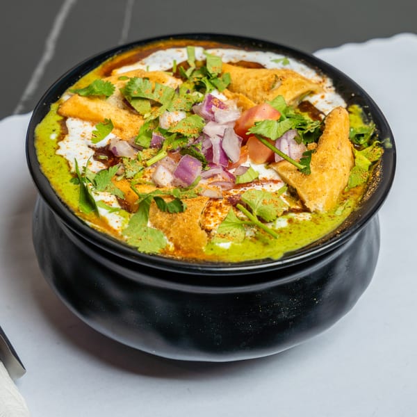 Maa Kitchen's Indian chaat, a vibrant dish with yogurt, chutneys, fried dough, onions, and cilantro.
